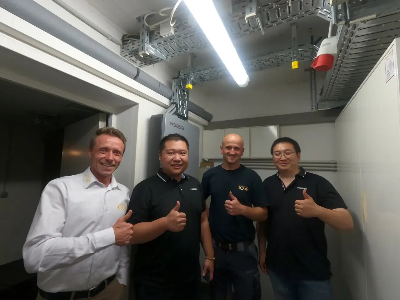 Installation team in front of the WEESS Powertower energy distribution system in the plant room